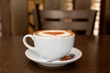 Cup with hot tasty coffee on wooden table in cafe, close up view