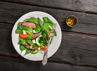 Meat salad and dressing near on the dark wooden table