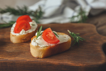 Delicious bruschetta with tomatoes on wooden board, closeup
