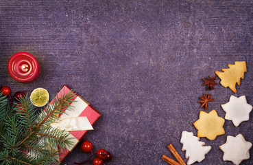 Christmas background with gingerbread cookies, dried citrus and fir tree. Decorations and gift box on rustic wooden board. View from above, top studio shot