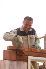 smiling bricklayer mason takes away the cement with trowel