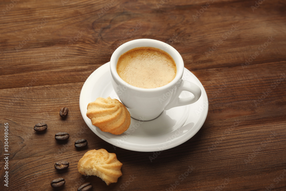 Wall mural cup of tasty coffee with cookies and beans on wooden table