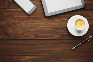 Tablet and cup of coffee on wooden background