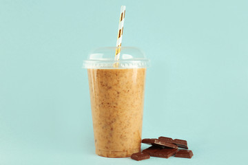 Tasty chocolate milkshake in plastic cup on colour background