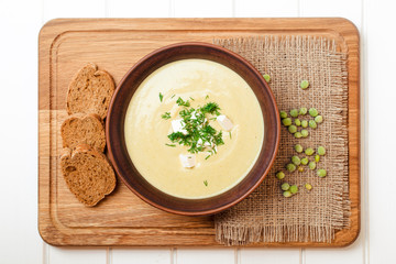 Peas cream soup on white wooden table.