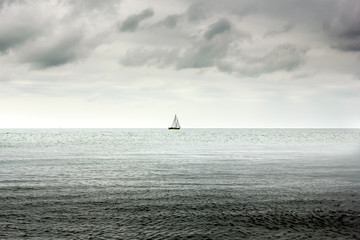 Single lone boat in Deep sea and heavy overcast clouds