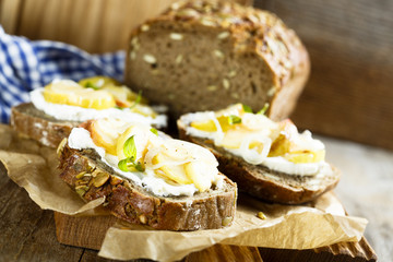 Sandwiches from homemade bread with pumpkin seeds, goat cheese, apple and onion