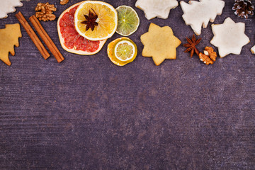 Christmas background with gingerbread cookies, dried citrus and fir tree. Decorations and gift box on rustic wooden board. View from above, top studio shot