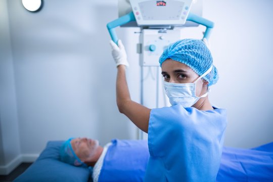 Nurse adjusting x-ray machine over patient