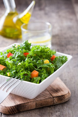 Kale salad in white bowl on wooden table