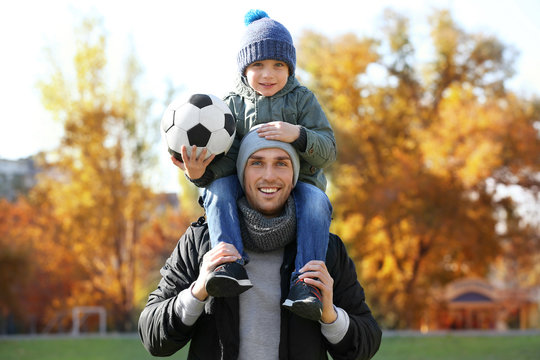 Father And Son With Ball On Soccer Pitch