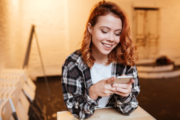 Happy redhead young lady chatting by her phone.