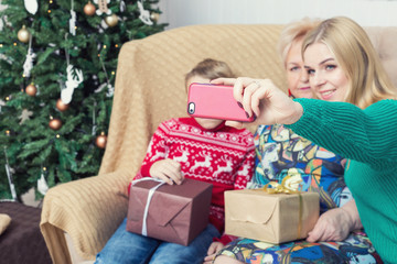 Happy family taking picture with smartphone on Chistmas decorations. Selective focus on smartphone