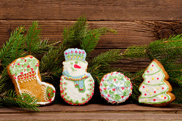 Gingerbread: sock, snowman, ball and fir-tree, spruce branch on a background of a wooden wall, closeup