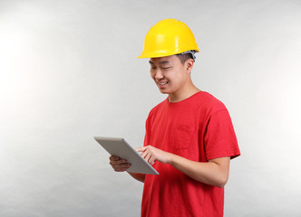 Asian warehouse worker with tablet computer on light background