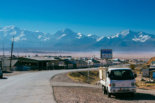 Car standing on the road with beautiful landscape of the Pamir mountains in South Kyrgyzstan on the background. The village of Sary-Mogul.