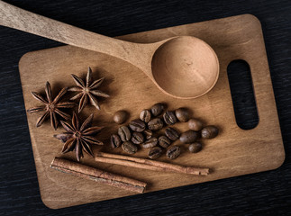 Fototapeta na wymiar coffee, star anise, cinnamon, spoon on wooden cutting Board and dark background