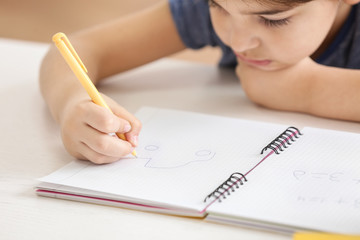 Cute little boy drawing something in notebook