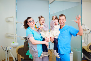 Two dentist with children in their arms smiling, laughing  the dentist's office