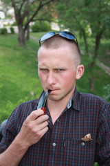 Fashionable man with short hair, a stern face smoking a pipe in a plaid shirt