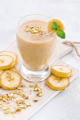 banana milkshake in a glass on white board, vertical