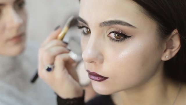 Professional makeup artist applying makeup to a model.