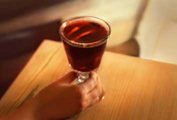 Female hand and glass of mulled wine on wooden table