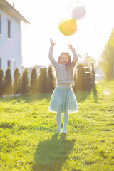 Joyful girl playing with balloons in sunset. Happiness, childhoo