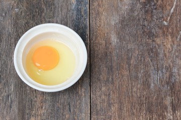 Raw egg in a bowl selective focus on wooden table