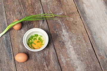 Raw egg in a bowl selective focus and onion on wooden table