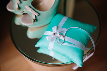 Wedding rings on turquoise cushion, open bride shoes