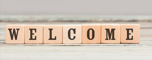 Word Welcome written with wood cubes on table