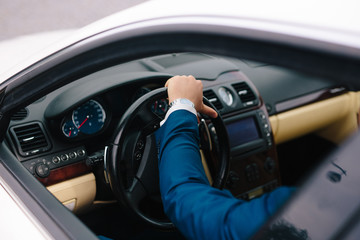 hand of a businessman at the wheel of a car