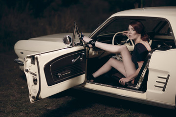 Fototapeta na wymiar Junge attraktive Frau trägt 50/60er Jahre retro Fashion in einem Ford Mustang Oldtimer