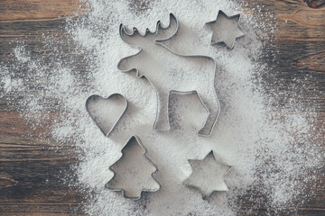 Five cookie cutters sprinkled with flour on wood