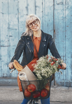 Smiling young woman with groceries on bicycle