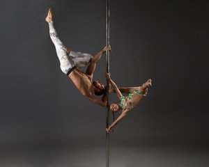 Pole dancers making exercises in pair studio shot