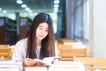 Happy asian student  young woman thinking with book in library