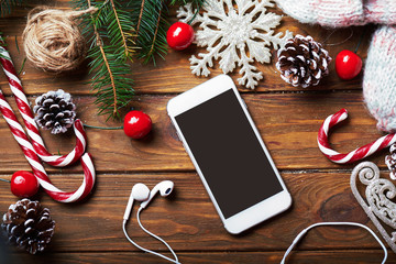 Smart phone mock up with headphones and rustic Christmas decorations for app presentation. View from above