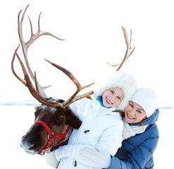 Happy little girl with mom hugging her reindeer. Winter playtime © natasnow