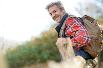 Hiker relaxing by fence on country track