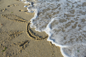 Fototapeta na wymiar Sea beach sand waves and drawings of sun, love and heart