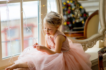 Cute little girl sitting by the window