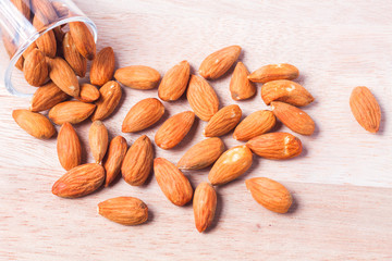 Almonds in brown bowl on wooden background