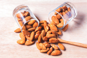 Almonds in brown bowl on wooden background