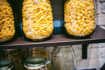 pasta in the jar. on kitchen shelves are different kinds of pasta in glass jars