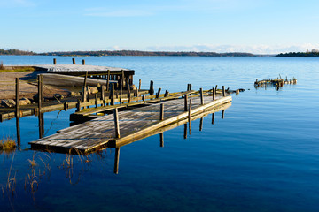 Abandoned wooden pier slowly breaking down to debris. Windless sea on this winter day. Frost on pier surface. Location Kuggeboda near Ronneby, Sweden.