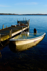 Obraz premium Sunken motorboat moored at a wooden pier and abandoned. Sea is motionless and calm.
