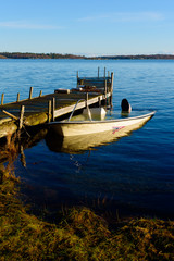 Obraz premium Sunken motorboat moored at a wooden pier and abandoned. Sea is motionless and calm.