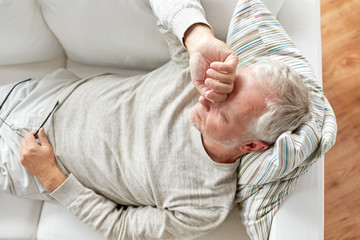close up of tired senior man lying on sofa at home